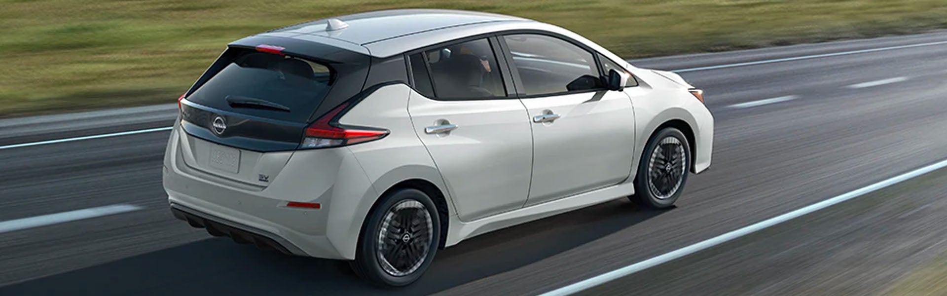 White 2025 Nissan Leaf driving on highway road