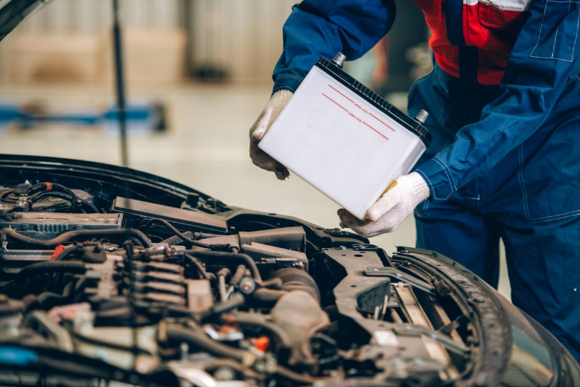Mechanic inspecting a car battery under the hood during routine vehicle maintenance.
